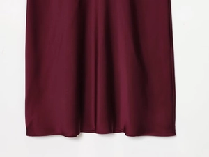 Close-up of wine red satin fabric showing smooth texture and fine hemline detail