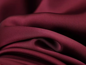 Macro detail of wine red satin fabric showing smooth silky texture and luxurious luster