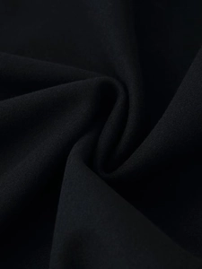Close-up of premium black wool blend fabric showing dense texture and matte finish