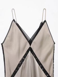Détail de robe en satin champagne avec col en V, dentelle florale noire et fines bretelles