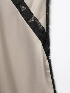 Détail du tissu en satin abricot avec coutures élégantes en dentelle noire sur la robe