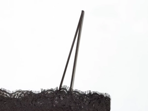 Detail of delicate eyelash lace trim and thin spaghetti strap on black satin top