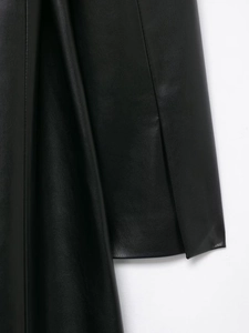 Gros plan du manteau en similicuir noir montrant la texture lisse et les coutures de qualité