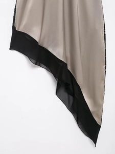 Détail de l'ourlet satiné champagne asymétrique avec bord en mousseline et dentelle noire