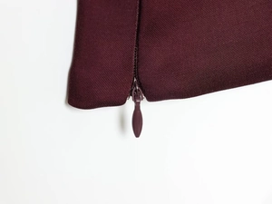 Dettaglio del top bordeaux con cerniera a goccia invisibile e trama in tessuto twill