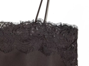Close-up of black satin camisole featuring delicate eyelash lace and slim straps