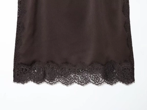 Detailed close-up of smooth chocolate silk fabric with elegant black lace trim on the hem