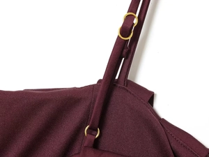 Dettaglio ravvicinato del top in maglia bordeaux con anello in metallo dorato sulla spalla