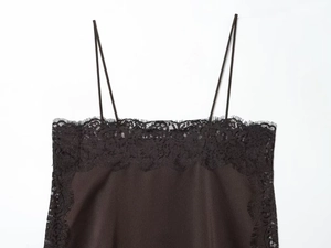 Close-up of black satin camisole featuring delicate eyelash lace trim and thin straps