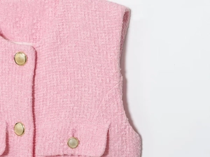 Dettaglio del tessuto in tweed rosa con eleganti bottoni in metallo dorato testurizzato