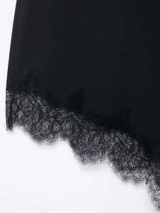 Close-up of black satin skirt hem featuring delicate eyelash lace trim and textured fabric