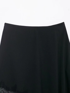 Detailed close-up of smooth black satin skirt featuring delicate lace trim at the hemline