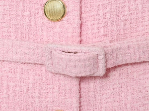 Vista dettagliata della trama in tweed rosa con bottone decorativo in metallo dorato