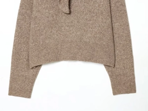Close-up of camel knit sweater showing soft plush texture and fine knit hem detail