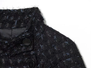Macro detail of navy tweed jacket featuring metallic silver threads and black buttons