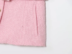 Dettaglio della trama in tweed rosa con bottone dorato decorativo e tasca rifinita