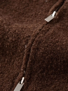 Detailed macro view of dark brown teddy wool texture and silver metal double zipper
