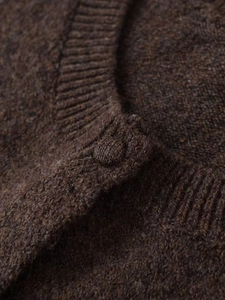 Close-up of fluffy dark brown knit fabric and fabric-covered round button on the cardigan