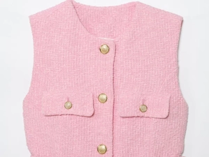 Dettaglio del tessuto in tweed rosa della maglia con bottoni dorati a rilievo