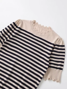 Detail of navy and beige striped knit top featuring delicate hollow scalloped neckline