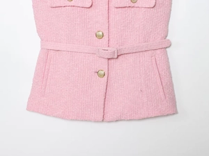 Dettaglio del gilet in tweed rosa con bottoni in metallo dorato e cintura in tessuto