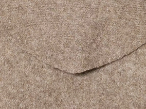 Close-up of camel knit texture and v-shaped edge stitching on long sleeve sweater