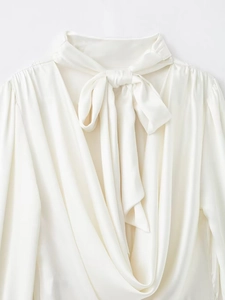 Détail d'une chemise en satin ivoire avec un nœud papillon élégant et un col en V fluide