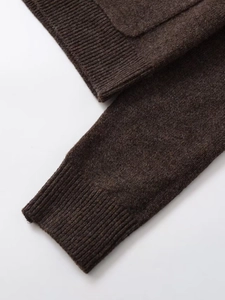 Detail of ribbed cuffs and hem on dark brown knit cardigan with soft texture