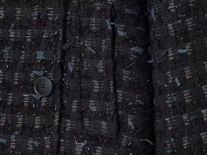 Close-up of black tweed fabric with woven blue threads and silver metallic accents