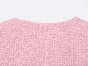 Dettaglio del collo del gilet in tweed rosa che mostra il tessuto a trama e lo scollo rotondo