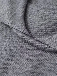 Détail du gilet en tricot gris montrant la texture fine et les bords côtelés