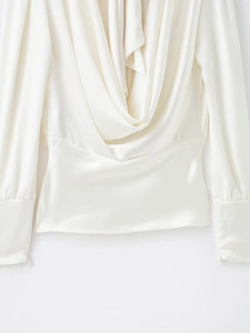 Détail de la blouse en satin blanc perle avec col bénitier et texture soyeuse