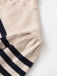 Detail of knit sweater with hollow-out floral neckline and striped puff sleeve texture