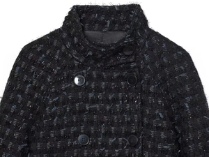 Detail of black tweed jacket with silver lurex, double-breasted buttons, and stand collar