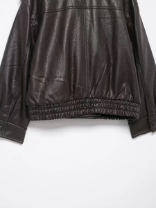 Vue détaillée d'une veste en cuir marron foncé avec grain texturé et ourlet côtelé