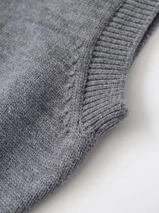 Gros plan sur le gilet en maille grise montrant la texture côtelée et la finition soignée
