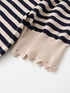 Detail of scalloped sleeve cuffs on a striped knit top with delicate pointelle stitching