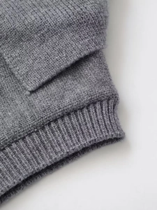 Détail de la texture d'un pull en tricot gris montrant le poignet côtelé et le tissu doux