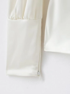 Détail de la manchette en satin blanc avec fermeture éclair invisible et plis délicats
