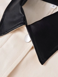 Macro shot of beige twill cotton jacket with black leather collar and silver button detail