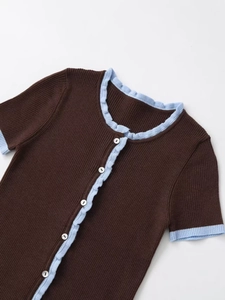 Detail of short sleeve knit cardigan featuring brown fabric with blue ruffle trim and buttons