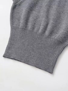 Gros plan sur le gilet en maille grise montrant la texture et l'ourlet côtelé