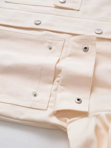 Detail of beige canvas jacket with silver metal snap buttons and neat stitching