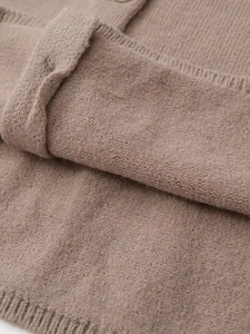 Detailed close-up of warm brown knit fabric showing soft ribbed texture and cuff stitching