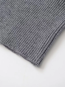 Détail macro de la texture en maille côtelée grise et coutures d'un gilet en tricot