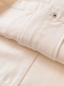 Detail view of beige twill fabric texture with silver metal rivet and stitching