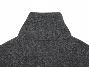 Detailed close-up of dark grey high collar wool cape coat with premium stitching texture