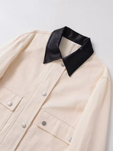 Close-up of beige canvas utility jacket with contrast black leather collar and silver buttons