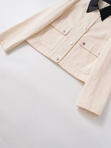 Detail of cream cropped jacket with black contrast collar and metallic cargo buttons