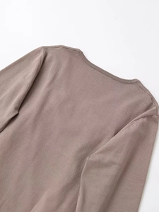 Detail of ribbed crew neck and fine knit texture on a slim fit brown sweater